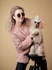 curly girl and poodle with glasses. A dog similar to its master. portrait in studio. modern, joke,...