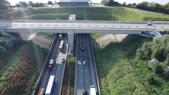 
Drone video of traffic on the highway driving under a bridge and into a tunnel with a nice sunflare at the top of the screen