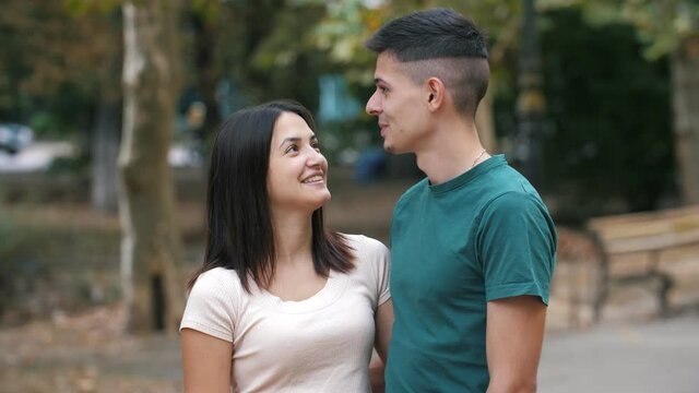 Laughing young people standing, hugging and talking to each other in summer