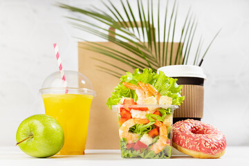 Healthy fitness food set of drinks, tropical shrimp salad in box, donut, packet in white interior with green palm leaf. Mockup advertising for delivery service, take away restaurant, online order.