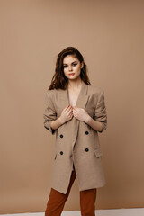fashionable woman posing on beige background in coat and trousers