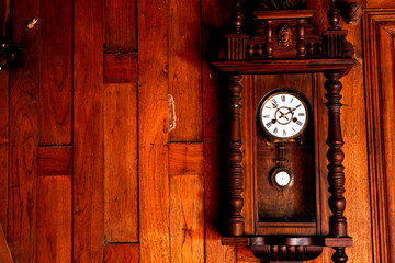 antique pendulum clock hanging on the wooden wall - obrazy, fototapety, plakaty