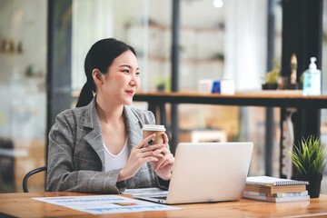 Asian businesswoman working on computer and drinking coffee at the office