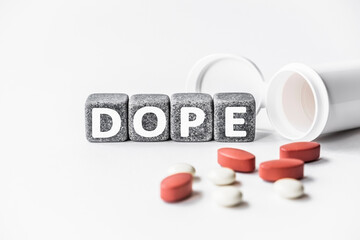 word DOPE is made of stone cubes on a white background with pills. medical concept of treatment, prevention and side effects. euphoria producing drug Cannabis Heroin Opium