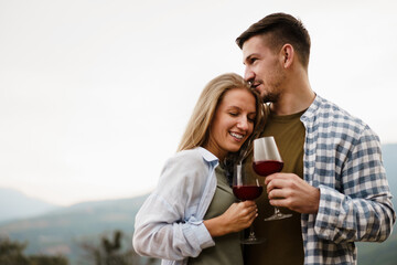 Smiling couple toasting wine glasses outdoors in mountains