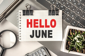 HELLO JUNE text on a notepad and laptop, office tools. Business, financial concept. remote training. Coffee break, ideas, notes, goals or writing a plan, invitation concept. Top view, flat lay.