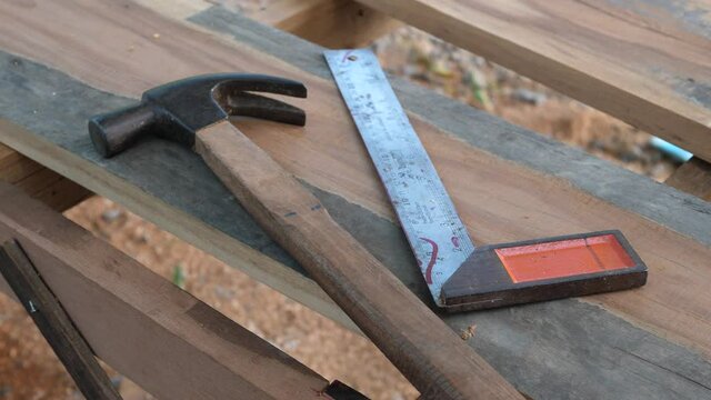 Hammer, try square tools, equipments in working place of making timber furniture outdoor in nature background. Concept of wood carpentry, hobby, DIY in free time, vintage retro location.