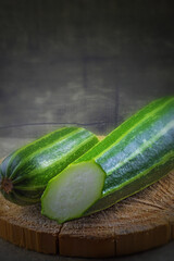 Two not whole zucchini are lying on a wooden round stand