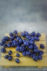 In the kitchen, on a wooden stand, there is a juicy vine with large berries