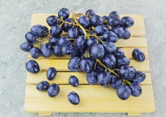 Ripe dark grapes with large fruits are lying on a wooden stand