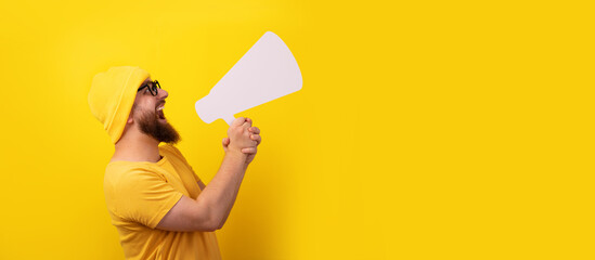 man screaming into  megaphone over yellow background, panoramic layout