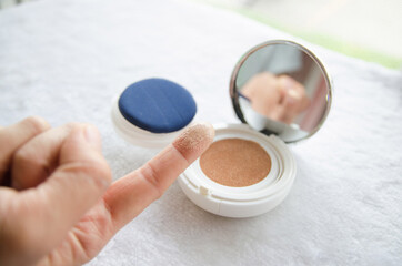 People review foundation cushion using their fingers to look at the powder texture, cosmetic cream as a background.