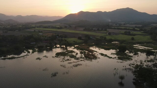Aerial view of Sunset over mountain range on agricultural land in countryside at Lam Taphoen reservoir