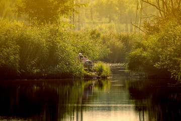 Fototapeta premium fisherman on the pond at sunset
