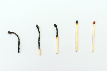 Row of burnt matches and whole one on white background, top view,closeup. Concept of different...