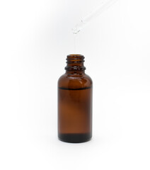 Serum in a brown glass bottle on a white background..