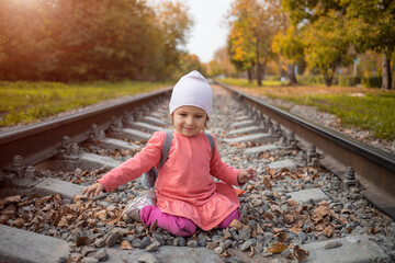 cute toddler playing with stones on the railroad embankment. dangerous games