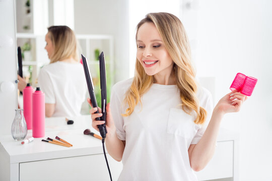 Photo portrait young woman in white outfit blonde keeping hair straightener bigoudi preparing for event