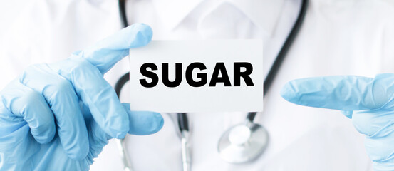 hands of a doctor in blue gloves hold a card with the inscription sugar, treatment and care of patients