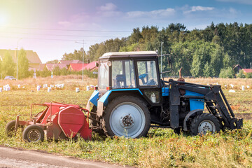 Modern wheeled agricultural tractor with harvesting equipment on an field