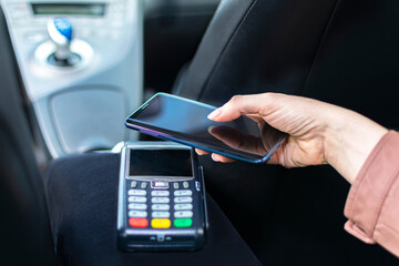 young woman paying with her smartphone in a taxi using a POS terminal. Selective Focus