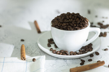 White coffee cup with coffee beans and cinnamon sticks