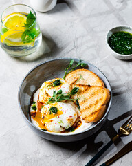 Cilbir or Turkish Eggs. dish served as mezze: poached eggs topped over herbed greek yogurt, then drizzled with hot spiced paprika olive oil. Turkish breakfast in a grey bowl on marble background