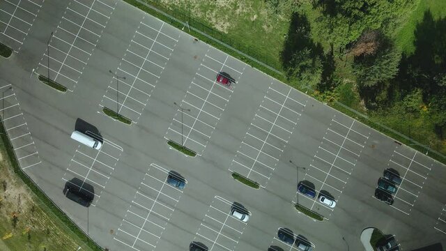 Large car park. There are few cars on it, a lot of free parking spaces. Aerial photography.