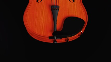 Violin on a dark background. Motion along the instrument with a dolly camera with a beautiful transition from black to black. Video to advertise violin courses, a musical instrument store or workshop.