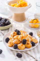 Dutch mini pancakes called poffertjes with blackberries and apple compot