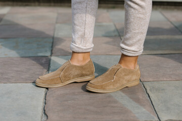 Portrait of fashionable women in beige pants and stylish suede loafer shoes posing in the street