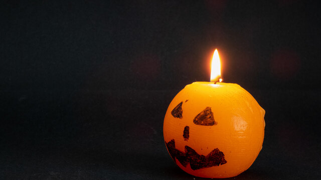 burning halloween orange candle and black background