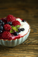 juicy berries in kremanka. Raspberries and blueberries with sour cream sauce and bowl on a wooden background. High quality photo