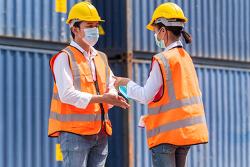 Factory workers wear face mask and safety dress measure body temperature and cleaning hand with alcohol sanitizer gel at outdoor warehouse - safety and health  protect coronavirus protocol concept
