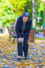 Senior woman having knee pain walking in park