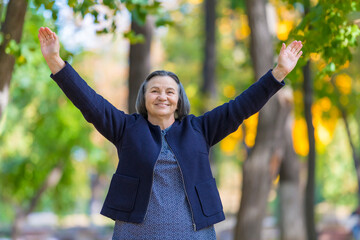 Happy woman with arms outstretched in autumn park