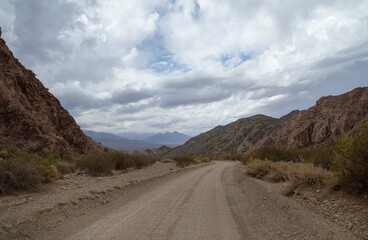 Road trip into the wild. Traveling along the empty dirt road across the arid desert and rocky mountains.	