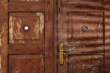 Old wooden dilapidated door in brown color with light shadows