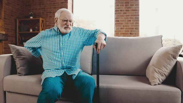Crazy grandfather in pain difficult stand up couch with walking stick help