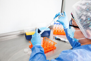 Young female scientist working in a safety laminar air flow cabinet at laboratory