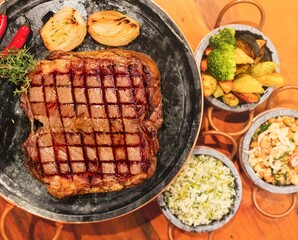 grilled meat with garnish. classic Brazilian accompaniments rice, beans, chili, onion and rustic potatoes