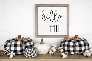 Modern farmhouse autumn shelf display with black and white buffalo plaid pumpkins and rustic hello fall sign