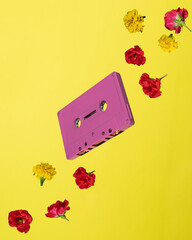 an audio cassette floating with a flower on a yellow background