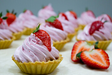 Sumptuous strawberry-topped tartlets with a delicate pink swirl, elegantly displayed alongside freshly sliced strawberries.