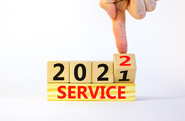Symbol of planning 2022 service new year. Businessman turns a wooden cube and changes words 'service 2021' to 'service 2022'. Beautiful white background, copy space. Business, 2022 service concept.