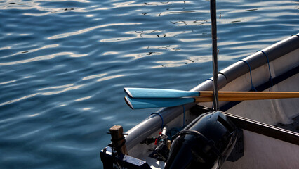 Small boats moored in a harbour floating in clear water with ripples and textures in bright sunlight
