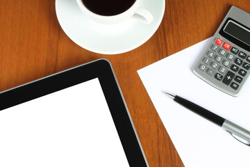 Tablet PC and stationery with cup of coffee on wooden background