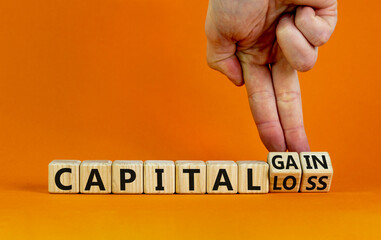 Capital loss or gain symbol. Businessman turns cubes and changes words 'capital loss' to 'capital gain'. Beautiful orange background. Business and capital loss or gain concept. Copy space.