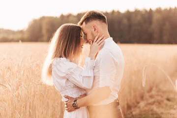 A young couple man and woman hug with tenderness in nature in the summer. Lovers