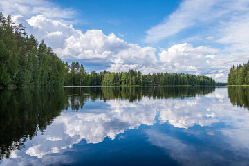 malerische Landschaft mit Bäumen, Wolken und blauem Himmel spiegelt sich in einem See